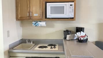Una cocina compacta con armarios de madera, microondas, cocina a gas y lavavajillas.