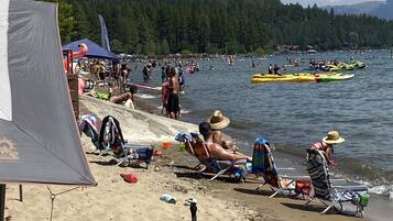 A beach scene with people, kayaks, and a tent.