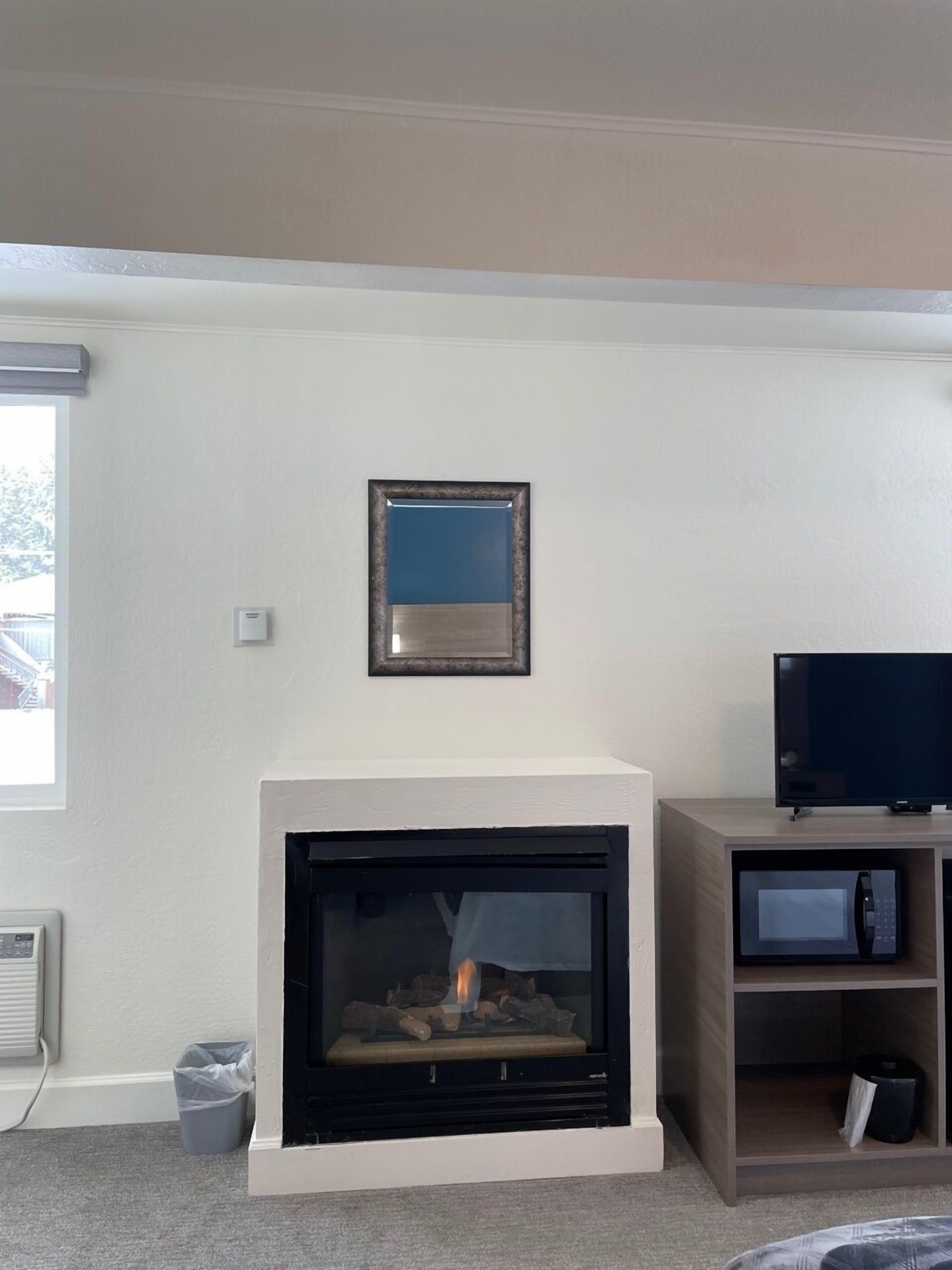 Un soggiorno con camino, una televisione su un mobile e un quadro appeso al muro.