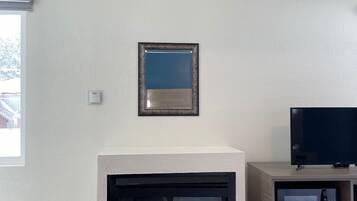 Un soggiorno con camino, una televisione su un mobile e un quadro appeso al muro.