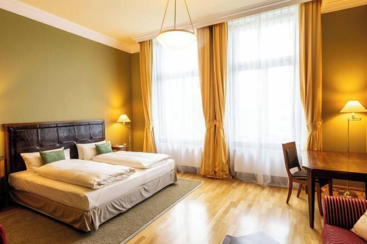 A hotel room with a double bed, a wooden headboard, a dining table, and a chair.