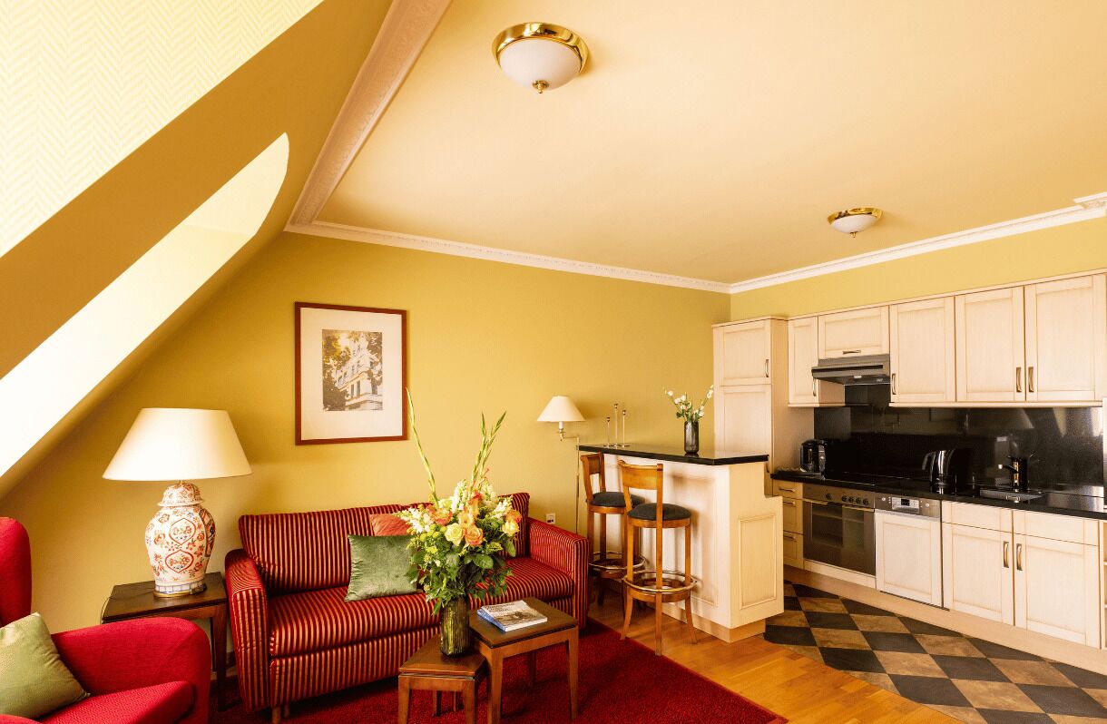A cozy living room with a sofa, a coffee table, and a dining area with a kitchen in the background.