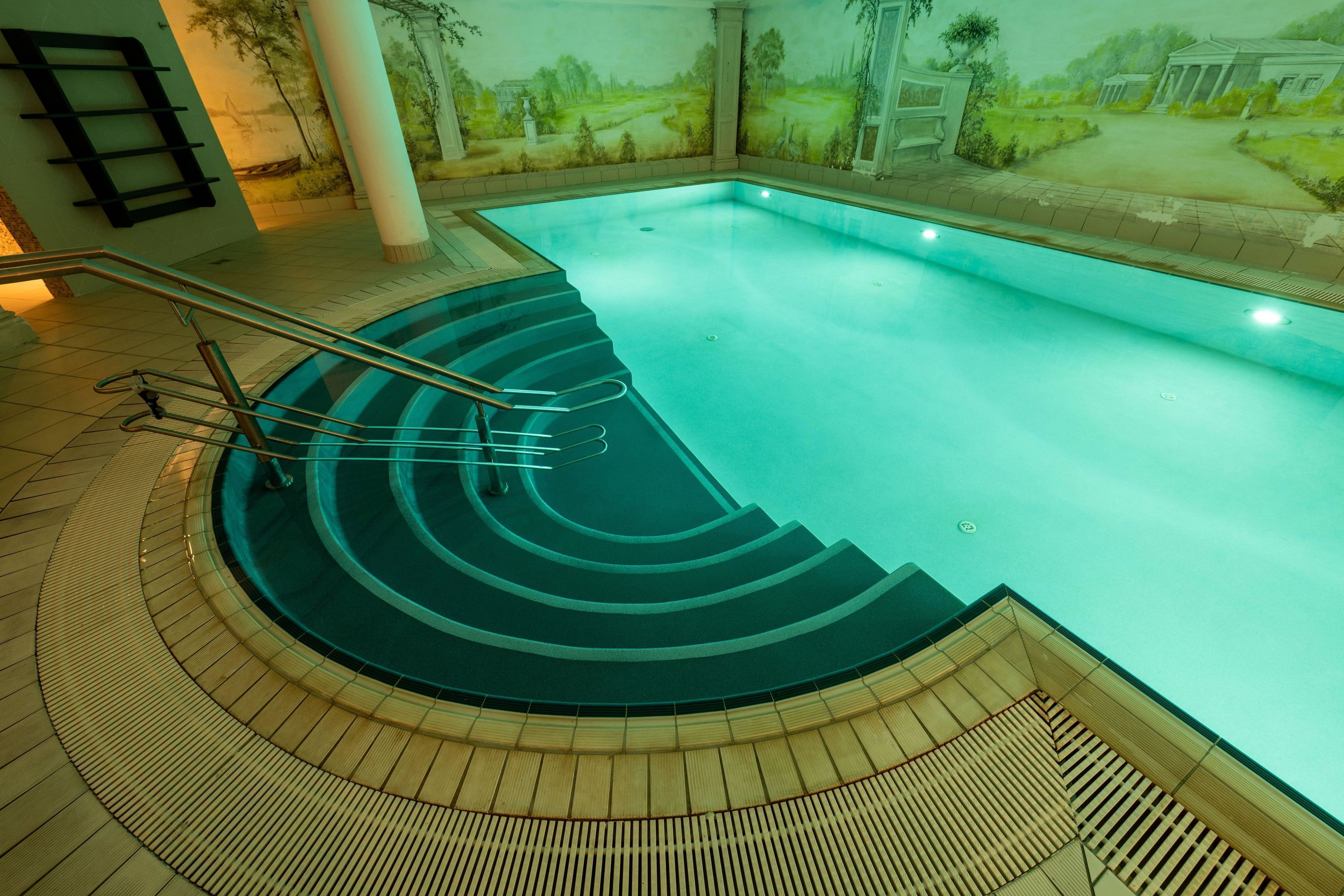 Ein Schwimmbecken mit einer Holzterrasse und Stufen zum Wasser.