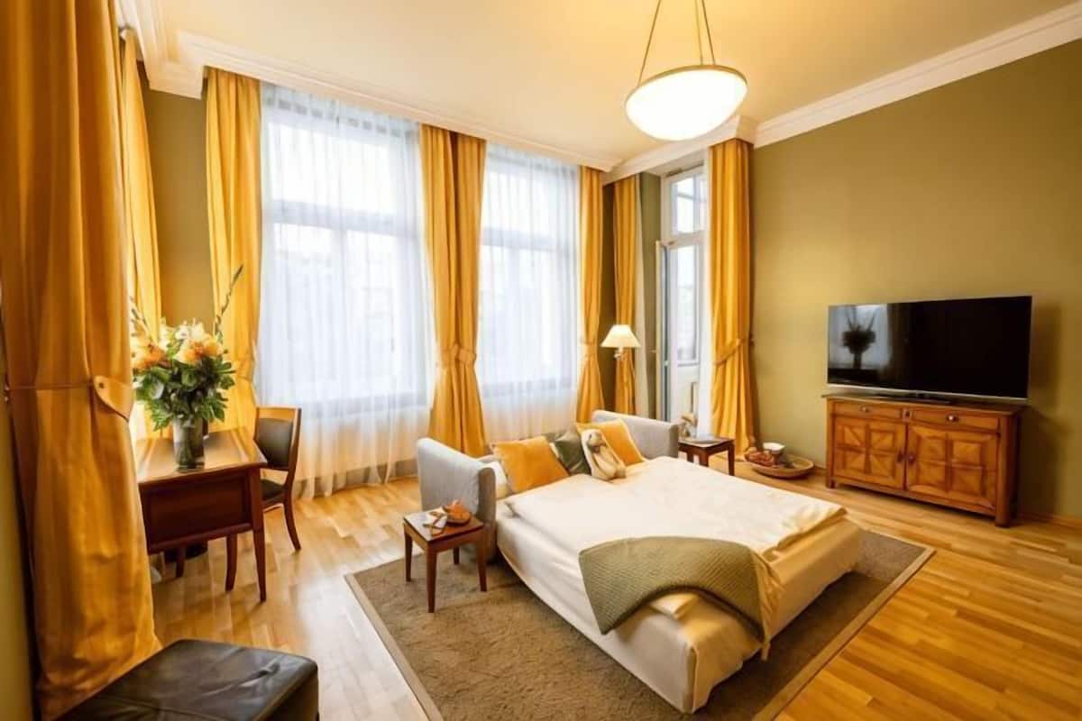 A hotel room with a bed, a TV, a desk, and a chair.
