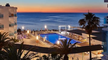 Una piscina al aire libre, sombrillas, sillones reclinables de piscina
