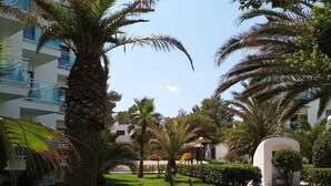 Un jardín bien cuidado con palmeras, césped y un muro de piedra.