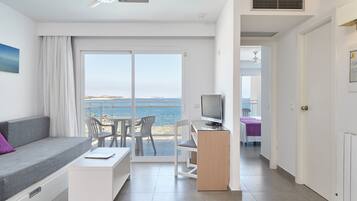 A modern hotel room with a balcony, a television, a desk, and a sofa.