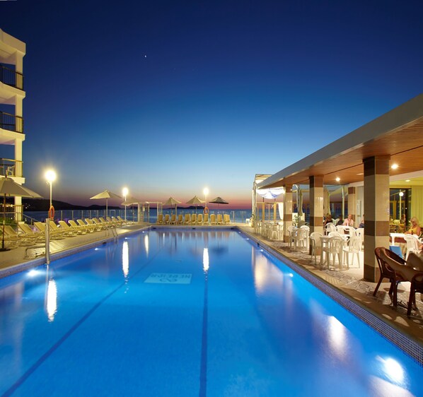 Una piscina al aire libre, sombrillas, sillones reclinables de piscina