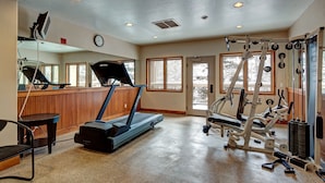 Un gimnasio con cintas de correr, elípticas y equipo de pesas.