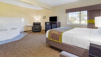 A hotel room with a bed, a massage chair, a desk with a computer, a TV, and a large window.