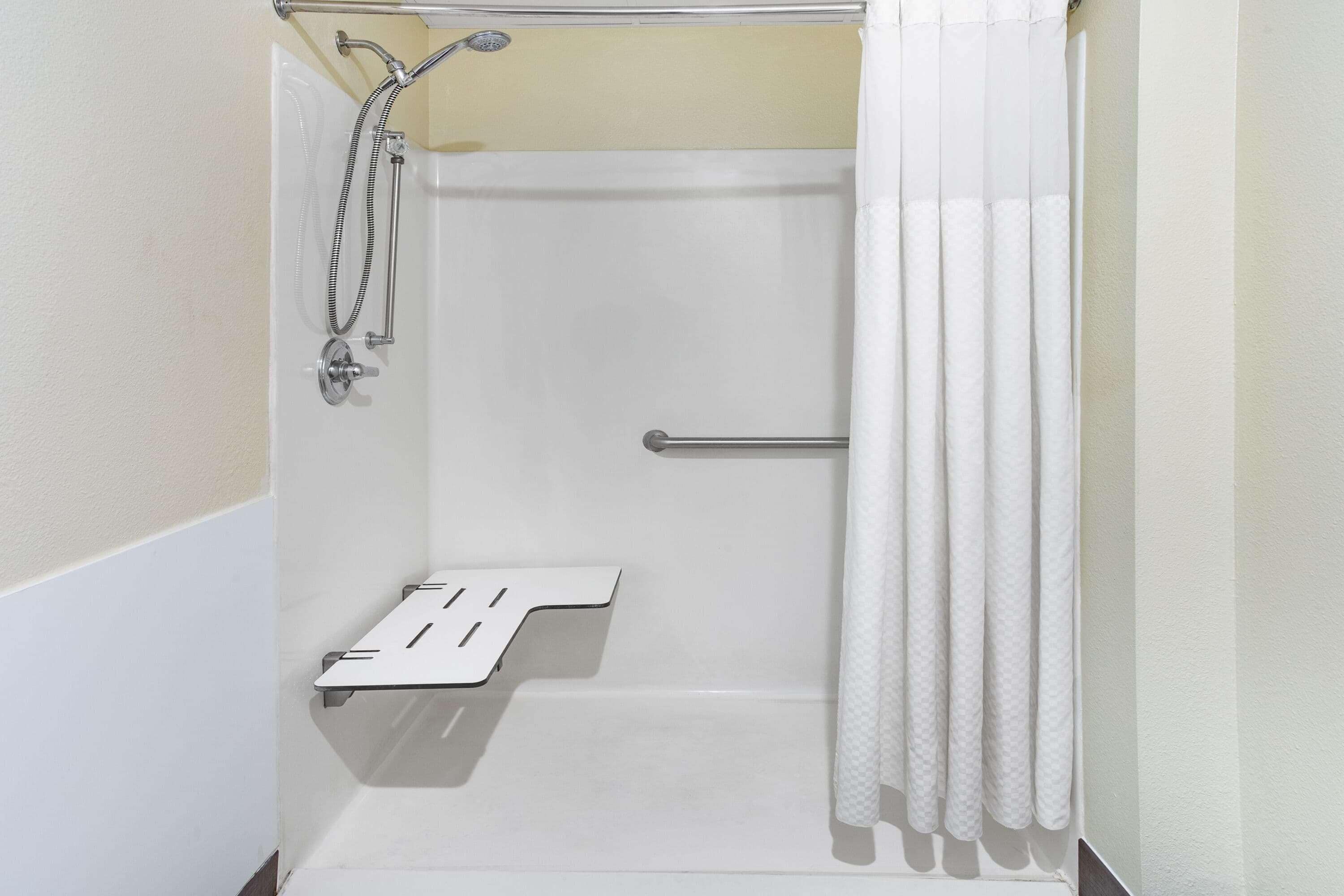 Ducha blanca con cabezal de ducha de mano, toallero y cortina de ducha.
