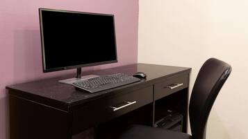 A dark wooden desk with a computer monitor, keyboard, and mouse.