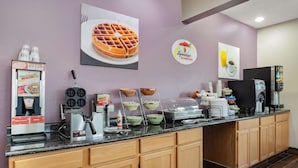 Een ontbijtbuffet met pannenkoekenijzers, siroopdispensers en een koffiehoek.