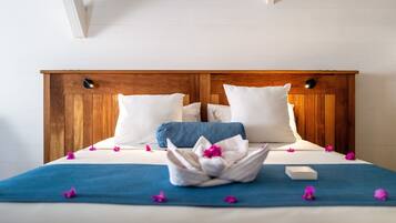 Una cama bien hecha con una colcha azul, almohadas blancas y un arreglo floral decorativo.