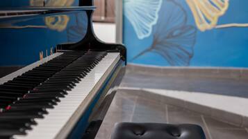 Un piano doté d’un clavier noir et blanc, un banc noir placé devant, et un mur bleu orné d’une fresque.