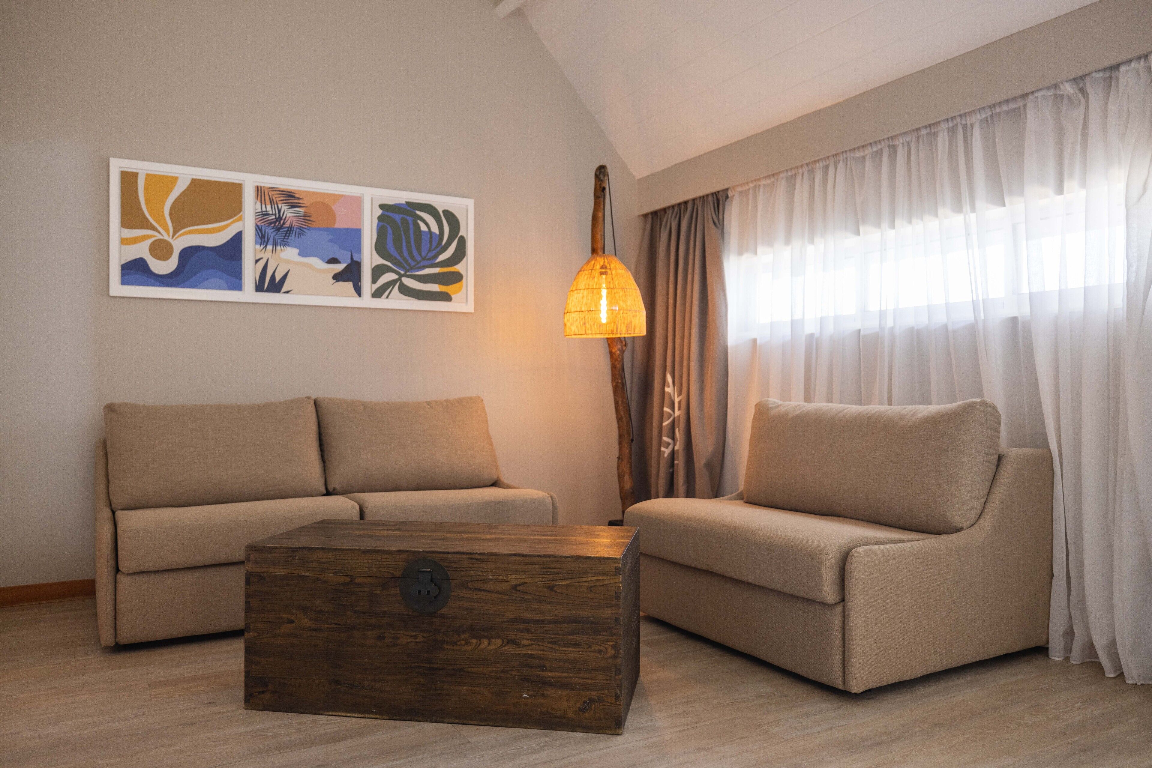 A living room with two sofas, a wooden coffee table, and a wall-mounted lamp.