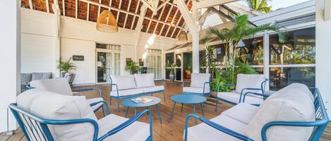 A covered outdoor seating area with wicker furniture and a wooden deck.