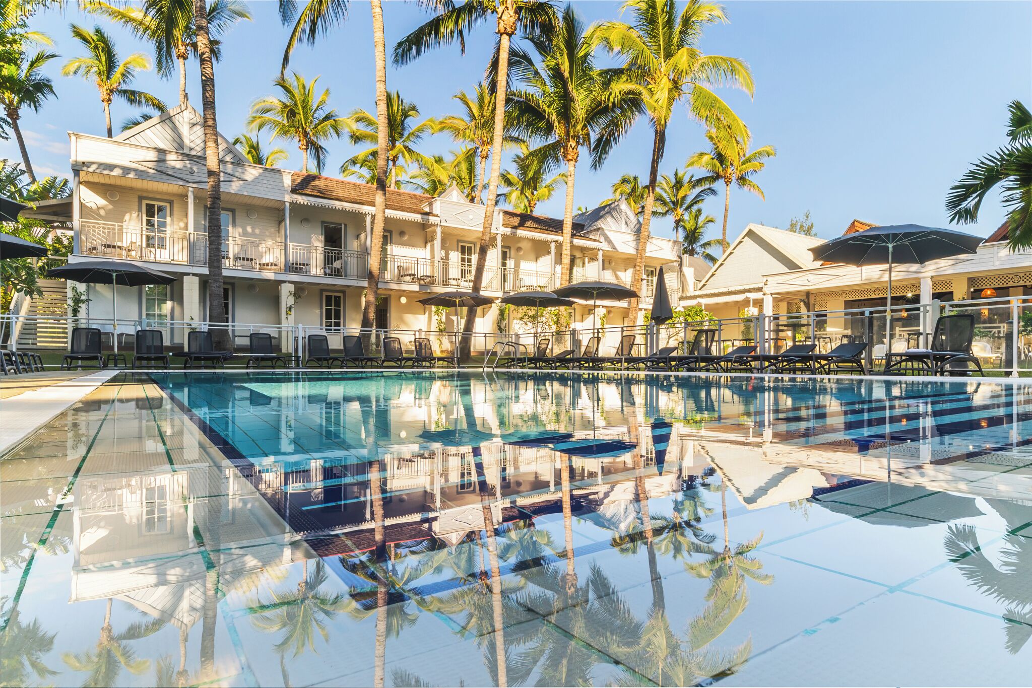 Una piscina al aire libre, sombrillas, sillones reclinables de piscina