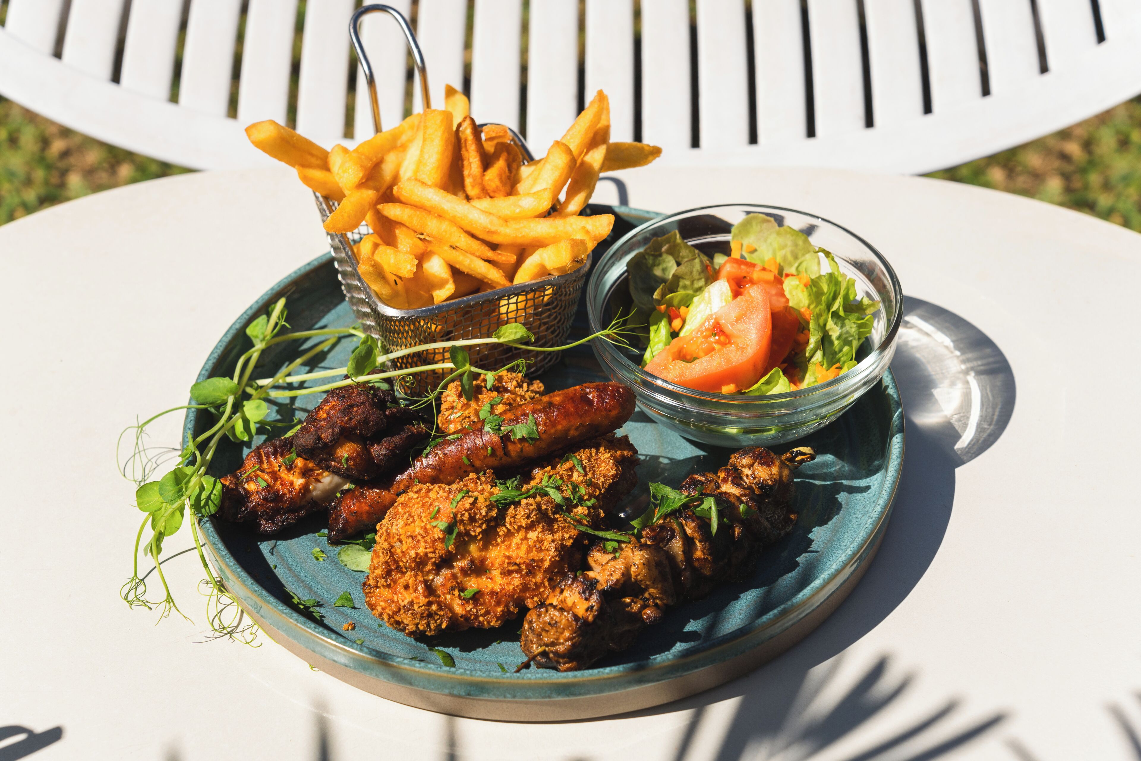 En tallrik med friterad kyckling, korvar, pommes frites och en sallad.