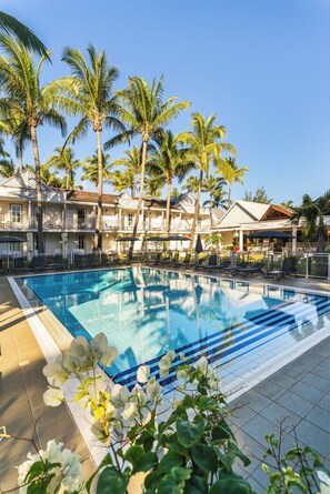 Una piscina al aire libre, sombrillas, sillones reclinables de piscina