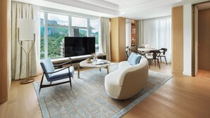 A modern hotel room with a large TV, comfortable seating, a dining area, and a view of the city. - Lanson Place Causeway Bay, Hong Kong (Hong Kong)