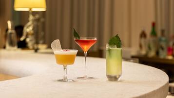 Three cocktails on a round table with a blurred background of a bar area.