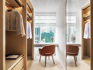 A modern hotel room with a walk-in closet, a seating area with a view of the city, and a large window. - Lanson Place Causeway Bay, Hong Kong (Hong Kong)