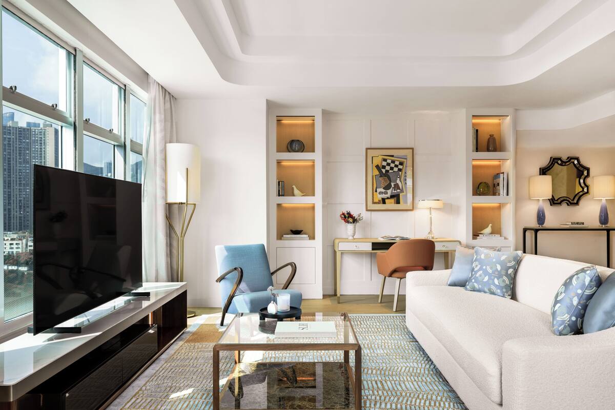 A modern living room with a large TV, comfortable seating, and a city view.