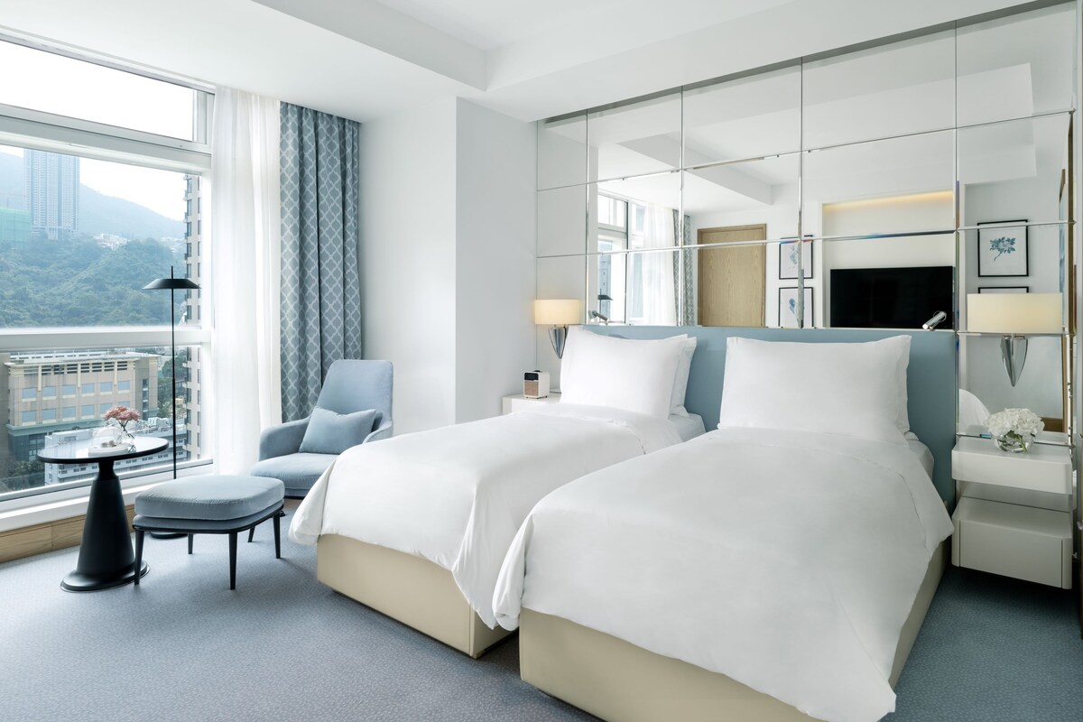 Une chambre d’hôtel avec un grand lit, une chaise, une petite table et une vue sur la ville.