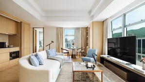 A modern living room with a sofa, a coffee table, a TV, and a city view through large windows. - Lanson Place Causeway Bay, Hong Kong (Hong Kong)