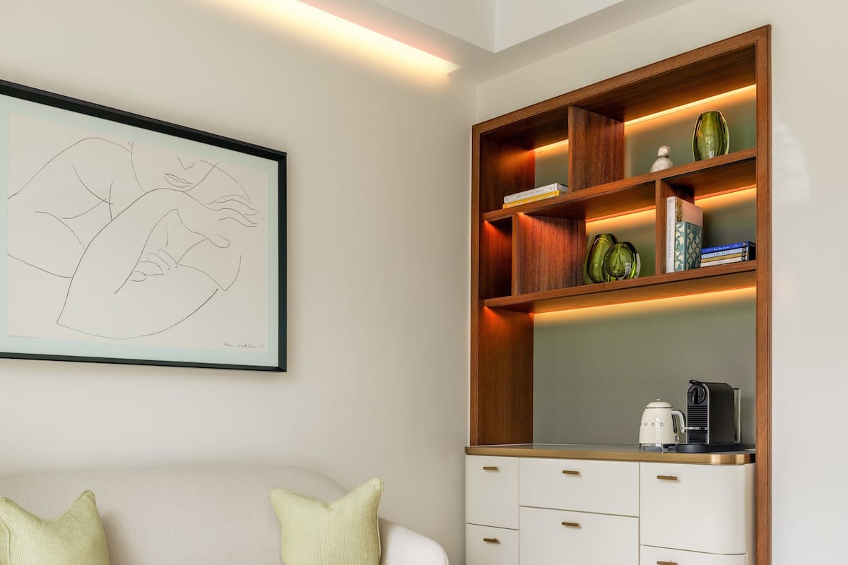 A modern living room with a white sofa, a marble coffee table, a wooden bookshelf, and a framed abstract painting.