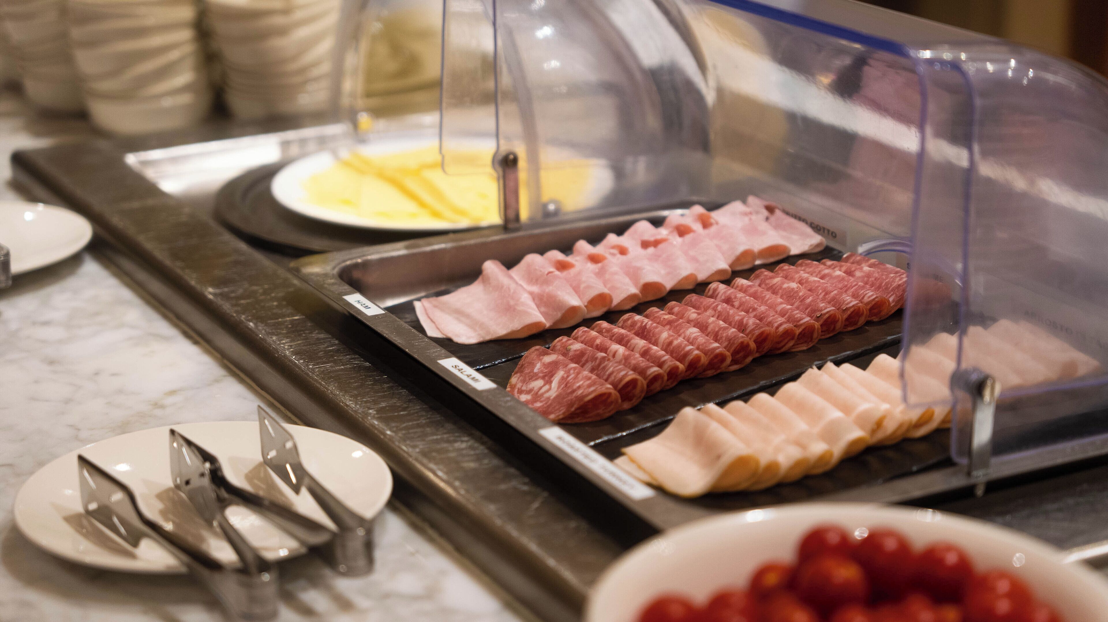 Buffet com diversos tipos de carne e uma tigela de cerejas.