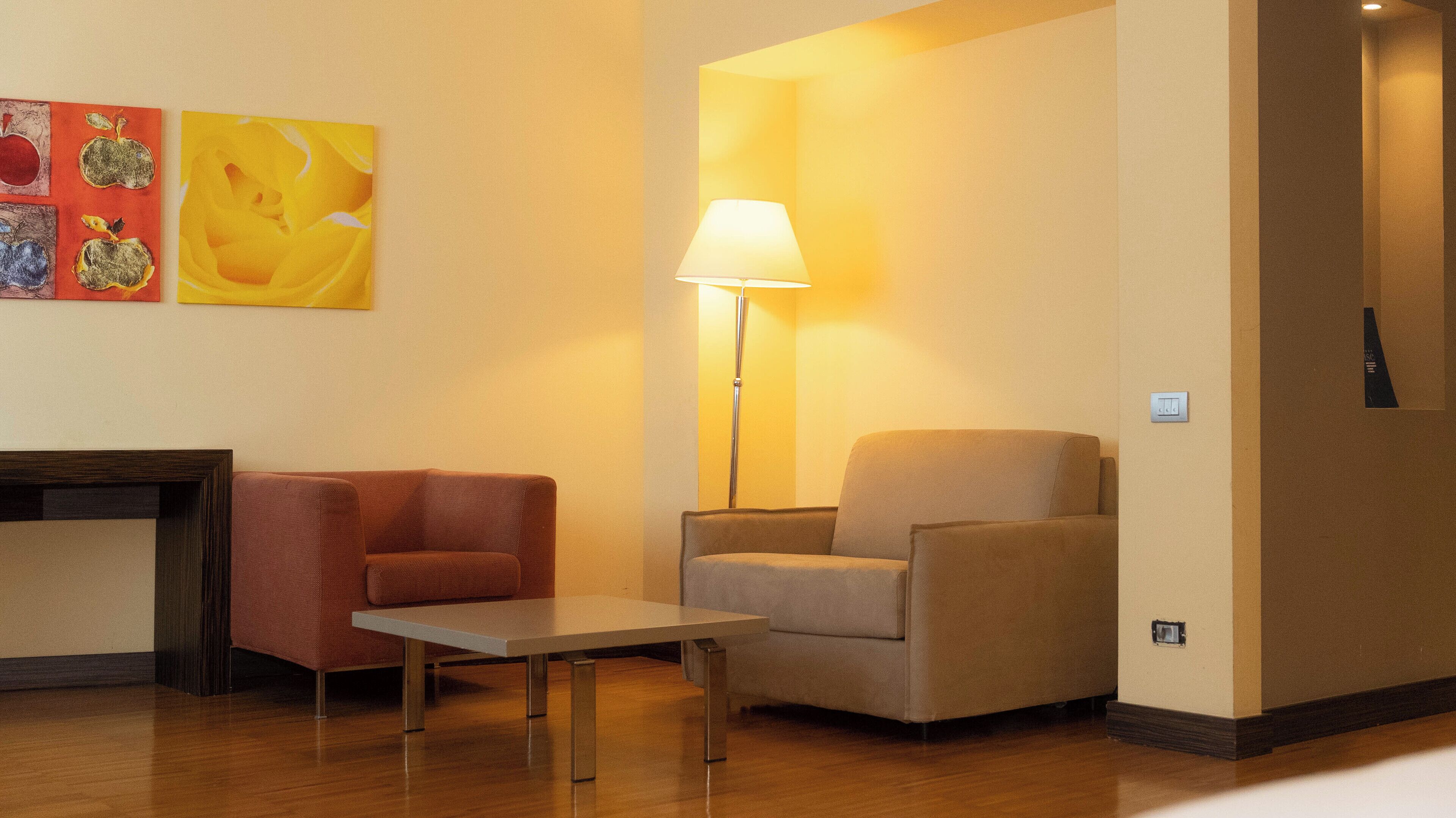 A room with a sofa, a chair, a small table, and a floor lamp.