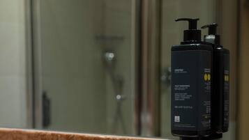 A bathroom with a marble countertop, a sink, a mirror, and a bottle of hand soap.