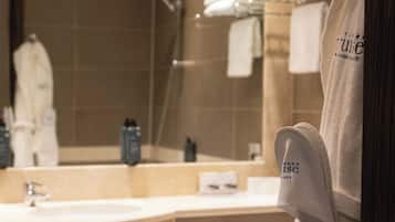 Un baño moderno con un espejo grande, una bañera y un lavamanos. Se ven toallas y artículos de aseo.