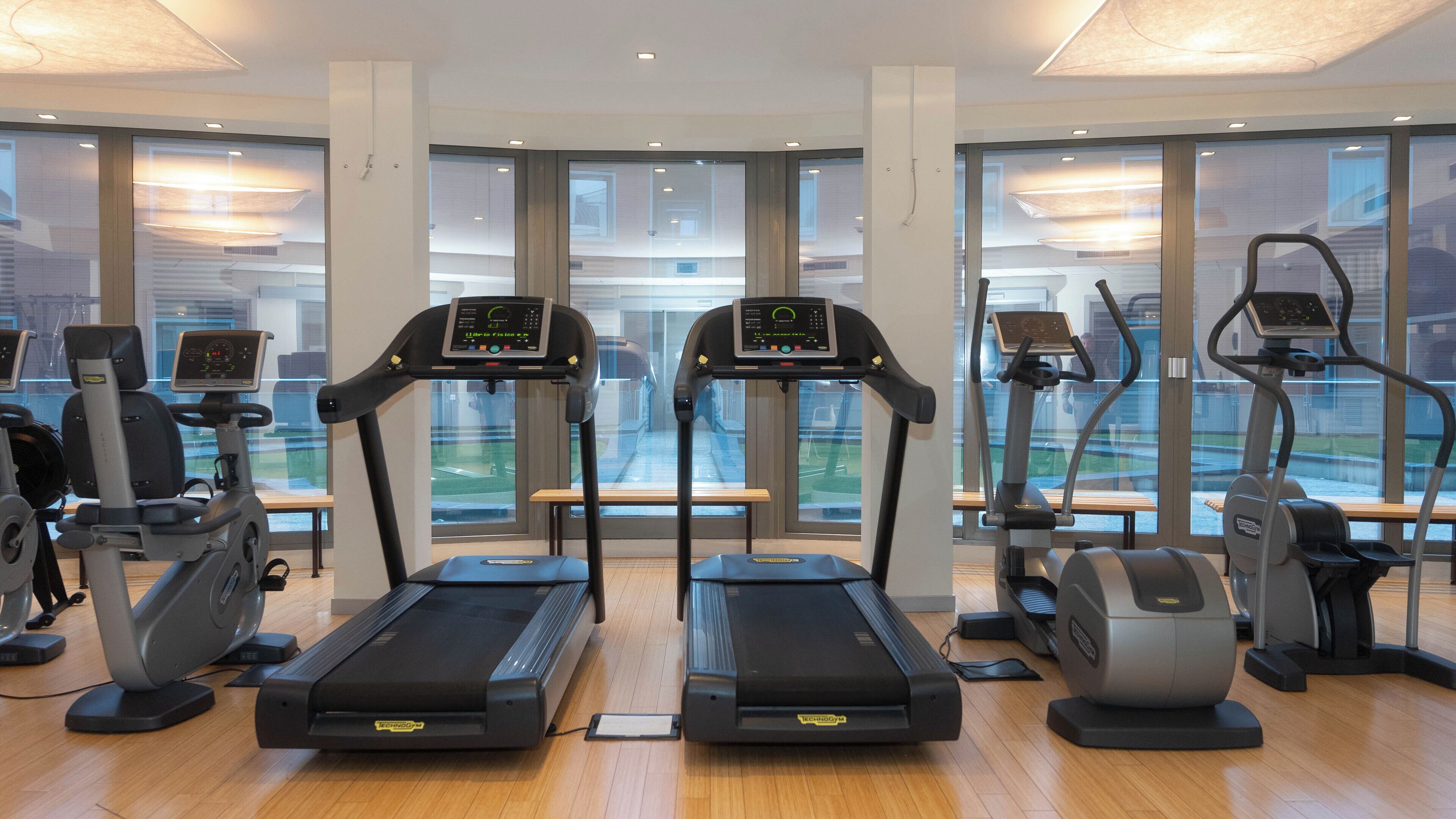 Une salle de sport moderne équipée de tapis de course, de vélos elliptiques et de matériel de musculation.
