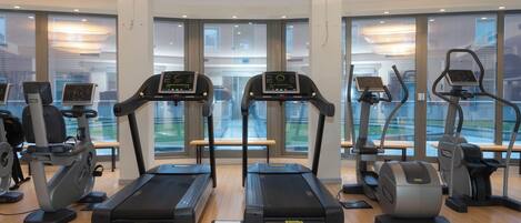 A modern gym with treadmills, elliptical machines, and weight equipment.
