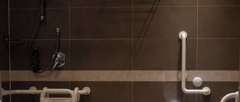 Een moderne badkamer met een douche, toilet en handgrepen.