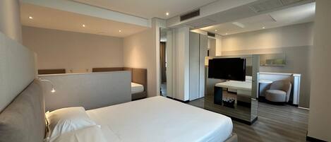 Una habitación de hotel moderna con una cama grande, un escritorio, una televisión y un área de descanso.