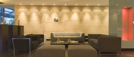 A modern lobby with a sofa, ottomans, a coffee table, and a floor lamp.
