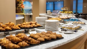 Un bufé con diversos pasteles y postres, incluyendo cruasanes y pasteles, dispuesto sobre una encimera de mármol.