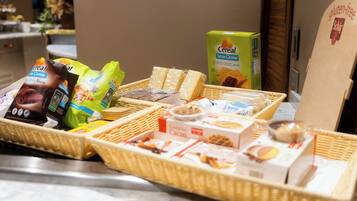 A breakfast buffet with various food items and boxes, including cereal and snacks.