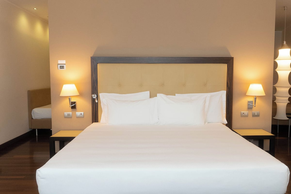 A hotel room with a large bed, two bedside tables with lamps, and a wooden headboard.