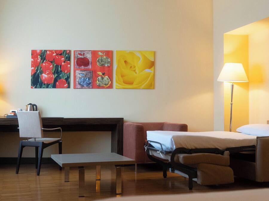 Habitación de hotel con escritorio, silla, cama y dos lámparas.