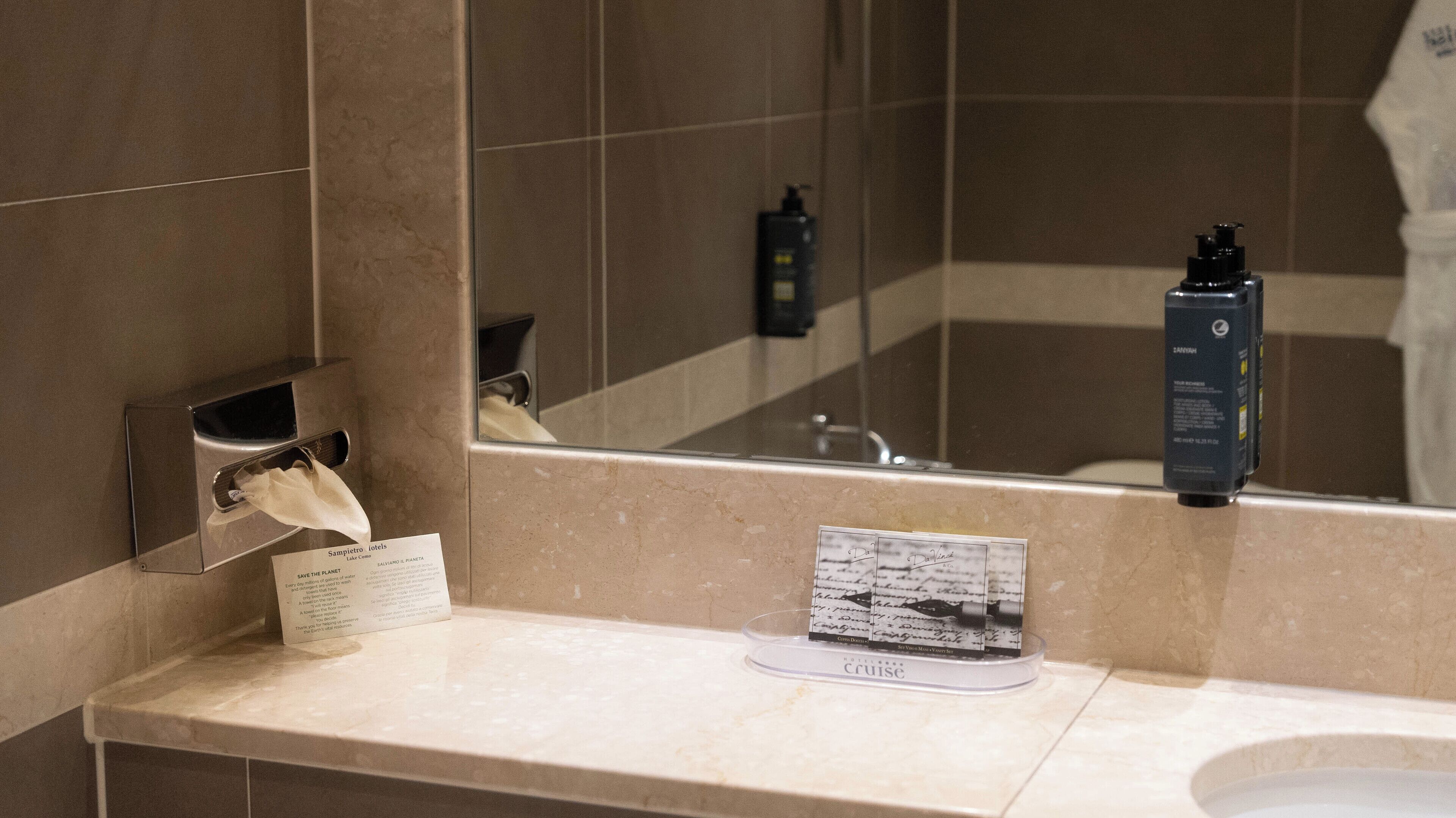 Une salle de bain équipée d’un miroir, d’un lavabo, d’un distributeur de savon et d’une boîte de mouchoirs.