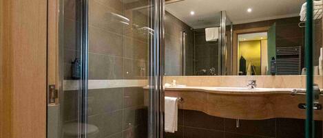 A modern bathroom with a glass-enclosed shower, a large mirror, and a checkered floor pattern.