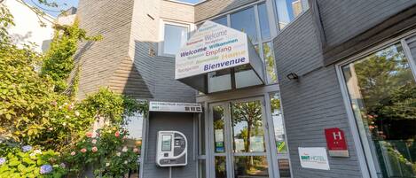 A hotel entrance with a sign displaying multiple languages welcoming guests.
