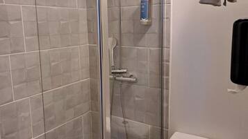 A modern bathroom with a glass-enclosed shower, a toilet, and a towel rack.