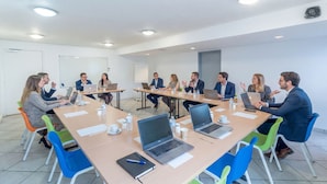 A conference room with a long table, laptops, and people engaged in discussion. - Brit Hotel Tours Nord (Tours)