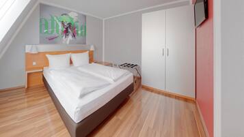 Un dormitorio moderno con cama, mesita de noche, armario y televisor montado en la pared.